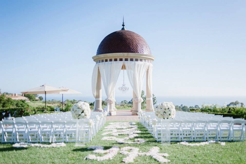 Magnificent Italian inspired rotunda overlooking Newport coastline styled with white linen drapery tied with hydrangea and rose floral bands.  Elegant rose petal design beginning with the couples initials.