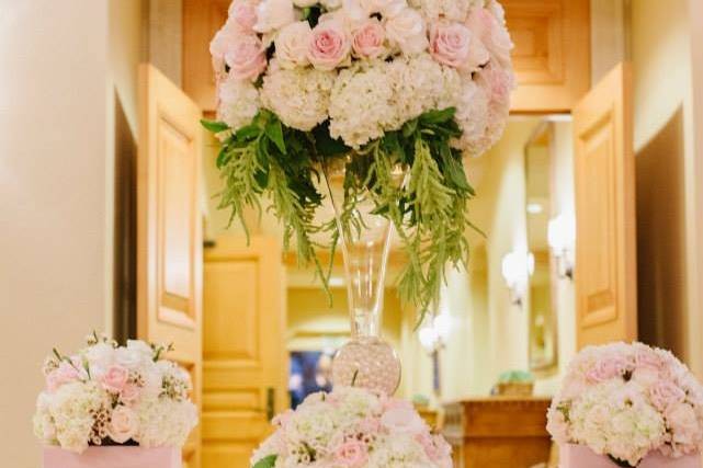 Lush and bright tablescape with centerpieces of differing heights. Designed with blush and white hydrangea and blush roses with complimentary accents.