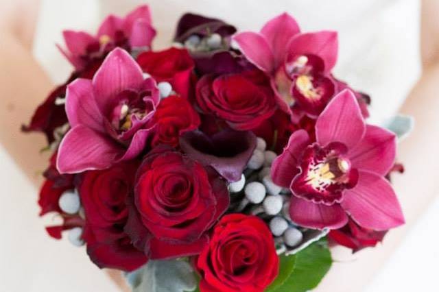 Bridal bouquet designed with red and deep red roses, burgundy cymbidium orchids, deep purple calla lilies, silver brunia and dusty miller.