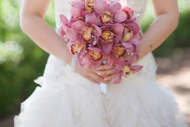 Elegant and simple monofloral bouquet of pink cymbidium orchids sprinkled with pearl strands.