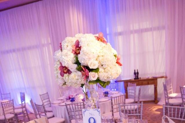 Tall centerpiece designed with white hydrangea, cream roses and pink cymbidiums perfect for an elegant reception.