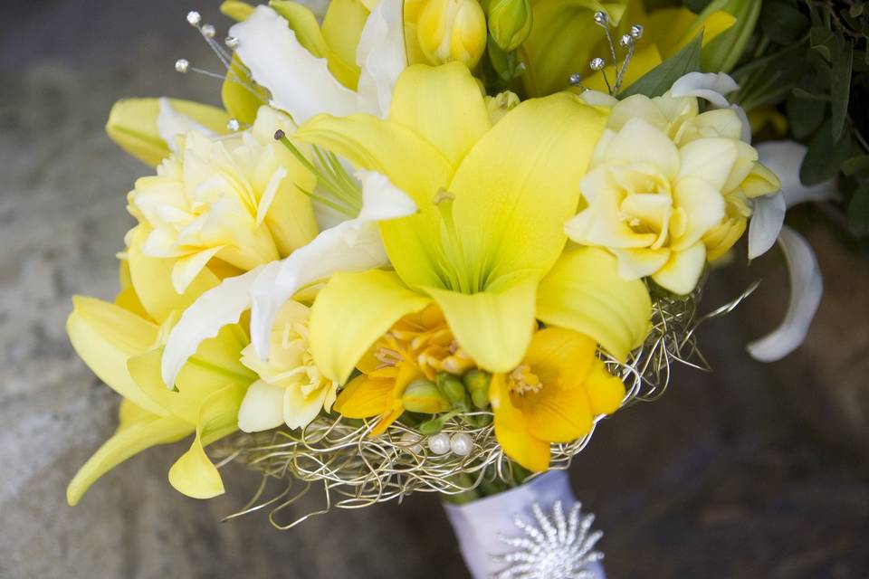 Bold and beautiful bridal bouquet designed with yellow and white lilies, yellow freesia with a silver wire collar.