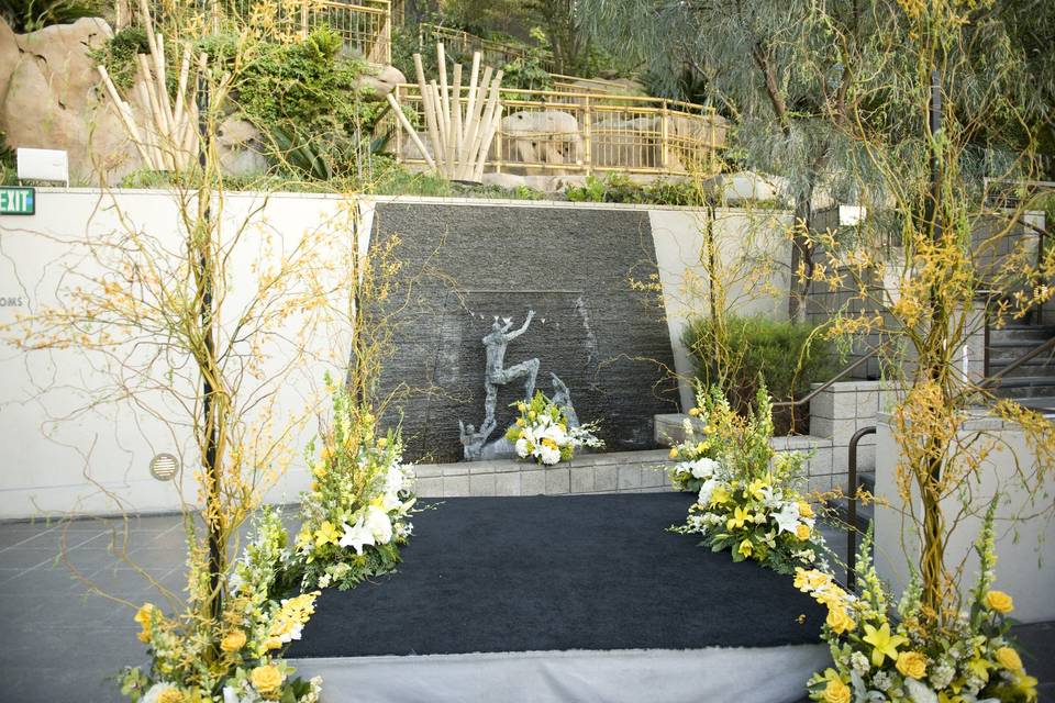 Simple yet elegant ceremony space, four corners designed with curly willow branches, oncidium orchids, yellow and white lilies, yellow snapdragons and yellow roses.