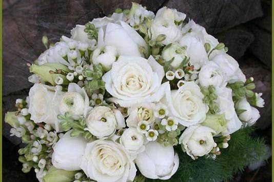 Round, hand-tied, fresh floral bridal bouquet of roses, ranunculus, waxflower, and lisianthus by Something Floral.