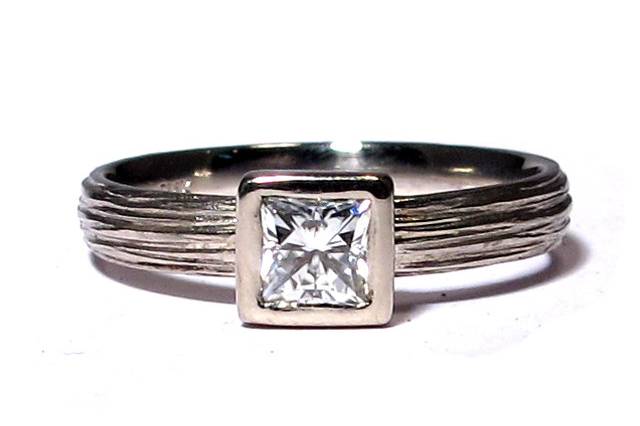 This textured Palladium band features a 4mm princess cut Moissanite, a great alternative to diamonds for cost and beauty. It comes in White Gold, Yellow Gold, Rose Gold, and Palladium. You can order a diamond if you prefer.