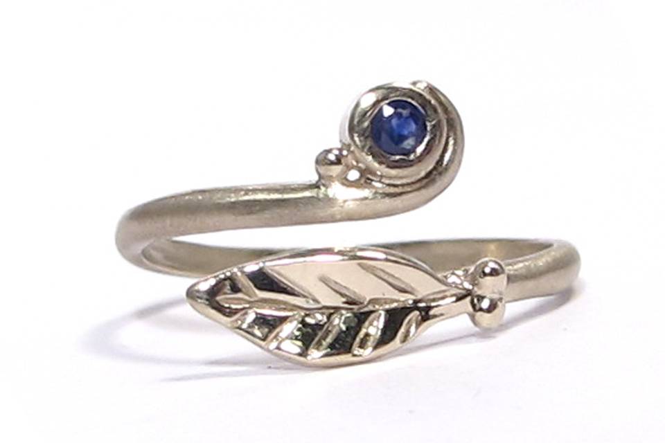 This organic leaf ring is made of 18K white gold and features a 1.mm, .015 carat blue sapphire.