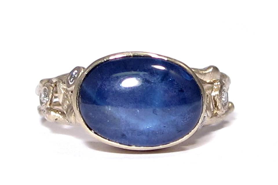 This organic leafy engagement ring features an oval star sapphire with two white diamonds on each side. One of a kind.