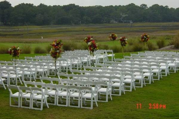 Outside ceremony overlooking the golf course at Colleton River.  Flowers were designed in decorative rod iron tiki torches and used for ceremony aisle decorations