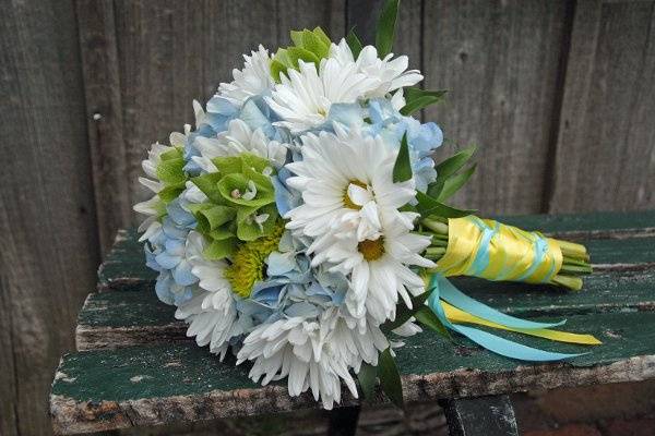 Bride's bouquet of blue hydrangea, white daisy pomps, green button mums, bells of Ireland, and ruscus leaves