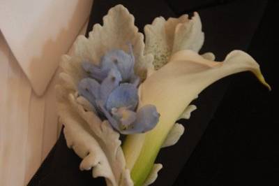 Bride's bouquet of purple lisianthus, Ocean Song roses, dusty miller leaves, purple waxflower, purple callas and crystal embellishment on the wrap.