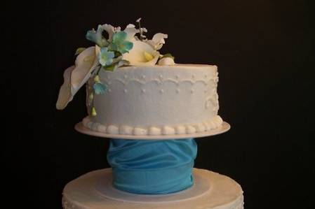 Buttercream Wedding Cake with White and pale Teal flowers.  Teal cuff separates the tiers.