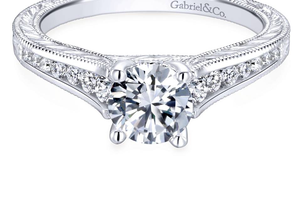 ER12306R3W44JJ	Strings of channel set graduated diamonds ascend the band of this white gold engagement ring, meeting on either side of your glittering center stone. Milgrain and engraved details complete the modern yet classic design.