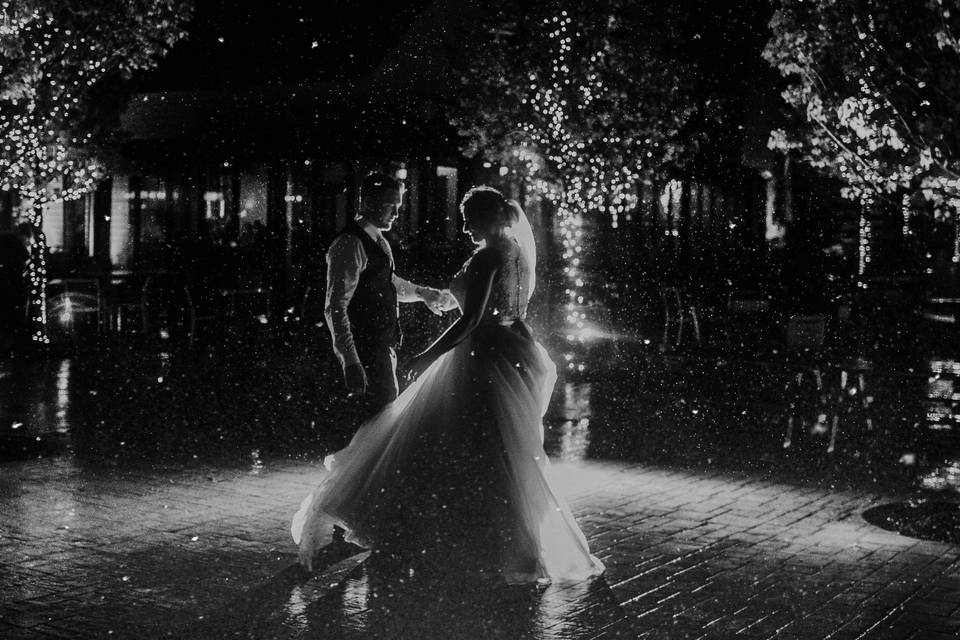 Newlyweds dancing in the rain