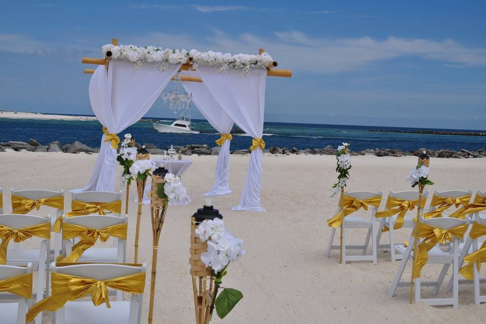 4 post natural bamboo arbor with flower topper, gold lame' sashes, white flowers and bamboo tiki aisle markers