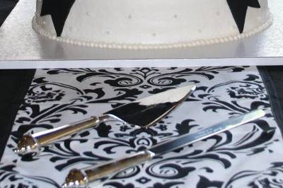 Three-tiered black and white cake frosted in buttercream with fondant bow and monogram