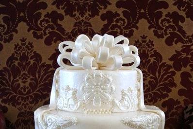 Fondant covered three-tiered cake with appliques and fondant bow