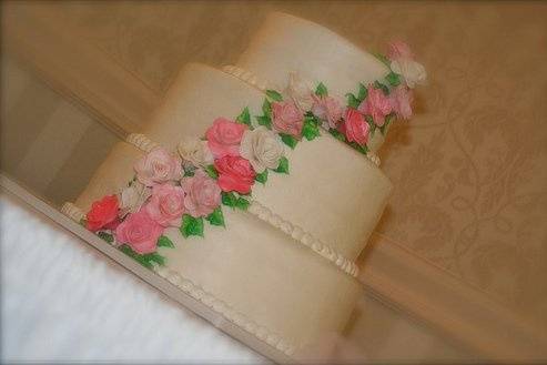 Three-tiered cake frosted in buttercream with cascading, hand-made sugar roses.