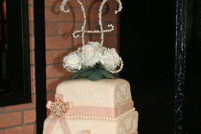 Three tiered square cake, covered in fondant with stenciling and fresh flowers