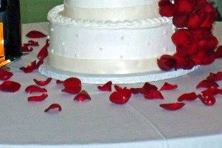 Featuring fresh cut rosebuds, this cake has a wealth of tiny pearls, each one accenting the sides of the cake. The cake is also banded by fondant, highlighted with super pearl coloring.