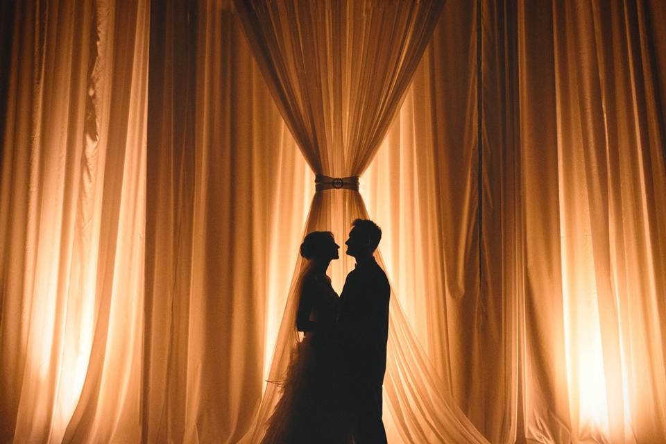 22' draped backdrop, floor to ceiling, at Ruthe Jackson Center.  Candlelight up lighting. Floral and cake pin spotting rounds out a breathtaking ballroom.