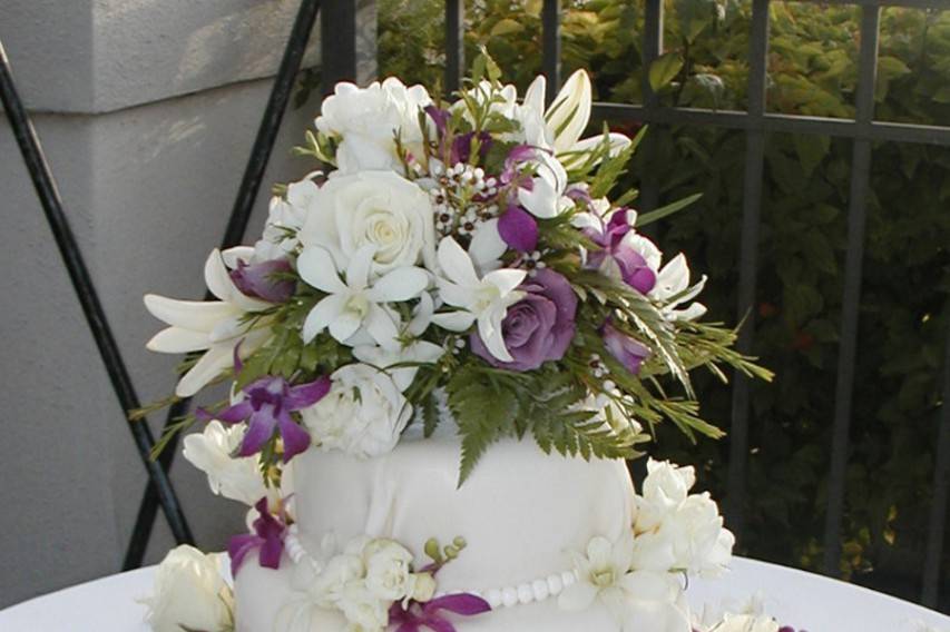 Three tier wedding cake with purple and white flowers