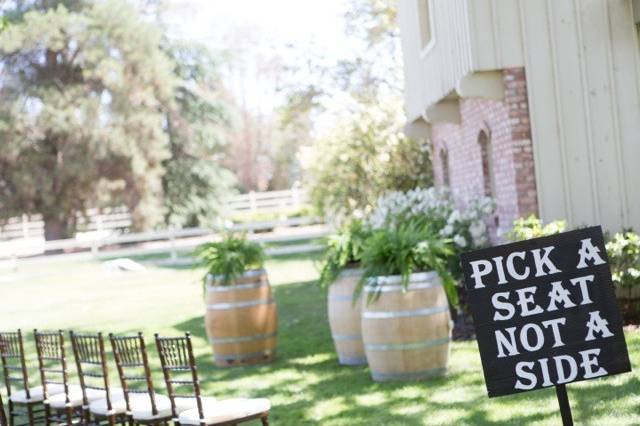 Wine barrels at the Ceremony site were adorned with lush, green ferns. Dark brown chivari chairs were provided for the guests along with a handmade sign proclaiming: 'Pick a Seat, Not a Side.'