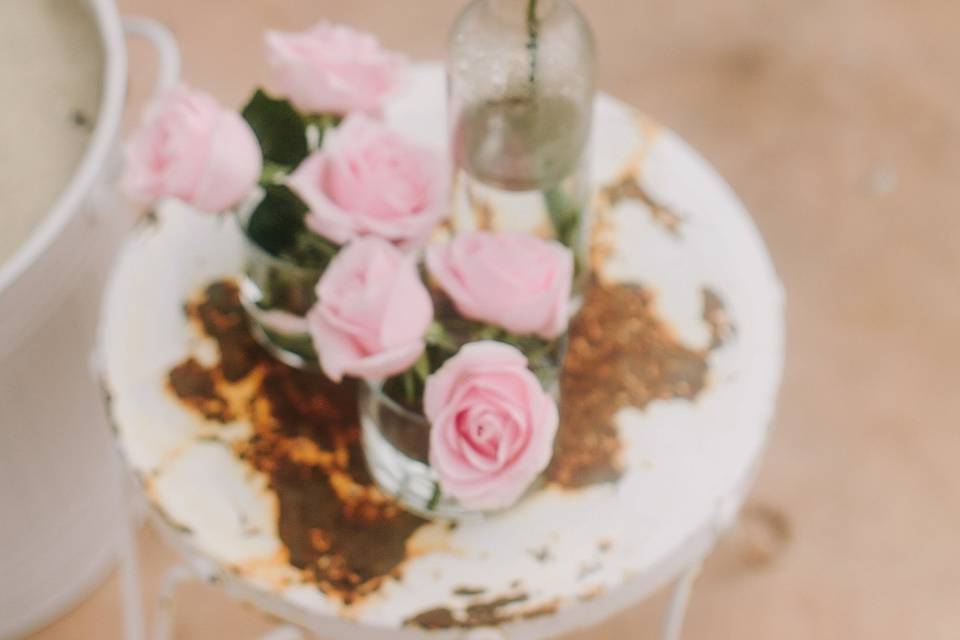 A small, chippy table adorned with pale pink roses.