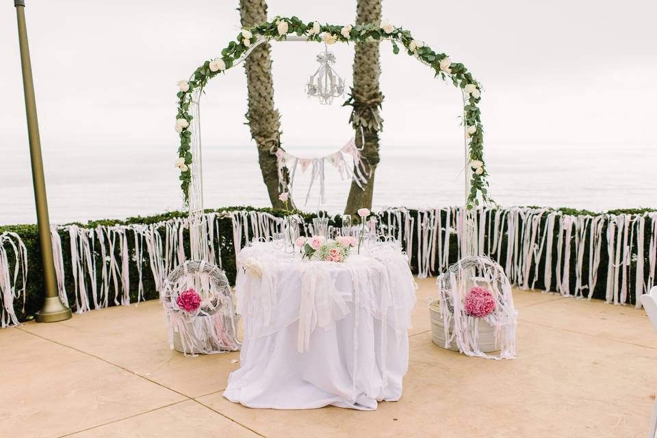 The sweetheart table was framed by a shabby chic arch decorated with a rose garland and crystal chandelier.