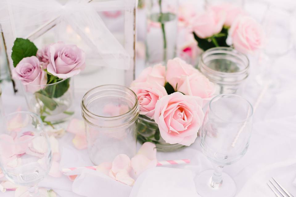 The tables were decorated with white candles, roses in varying size vases, mason jars for water goblets and striped  paper straws.