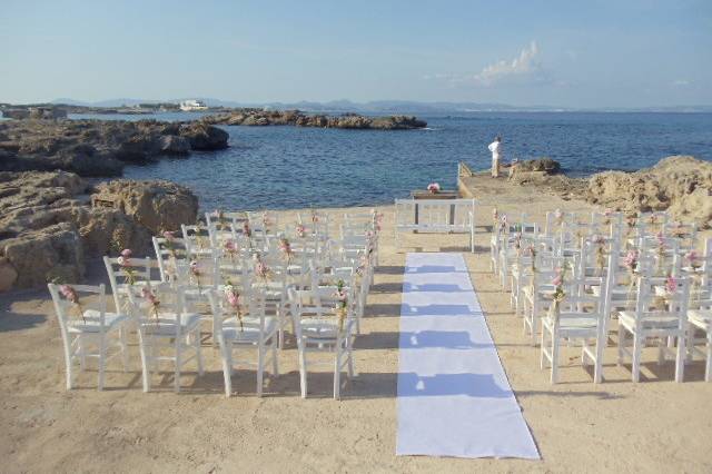 Chez Gerdi patio Ceremony site with the Baleric Sea for a most perfect backdrop. White wood chairs were decorated with flowers.