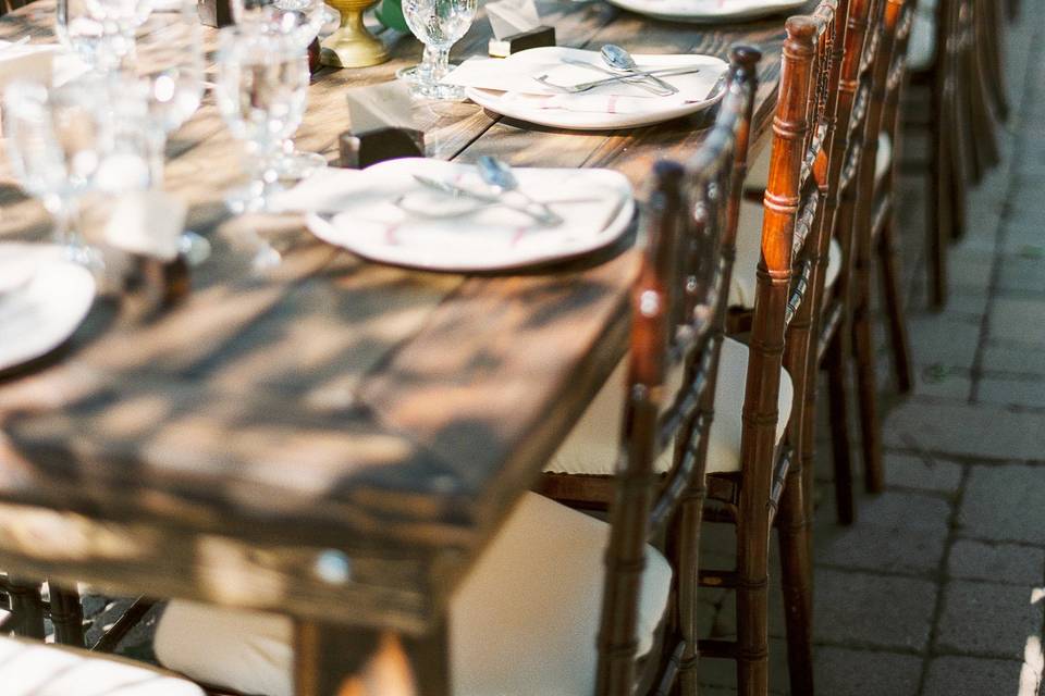 Long dark farmhouse tables and dark wood chivari chairs were placed on a beautiful stone patio under the oaks.