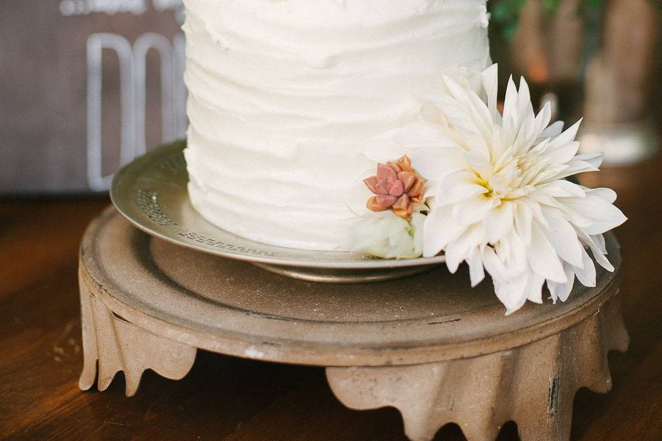 The Sweetheart table had glass floral garlands hanging from the branch of an oak tree that was directly above their vintage wood table. Fun 70's-esque planters in gold and bronze and amber glass bowls held succulents and varying floral. Floral design by Adornments. Photography by Jamie and Chase Photography.