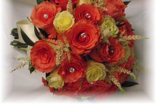 Light orange and ivory roses mixed with astible and adorned with rhinestones in a hand tied bouquet.