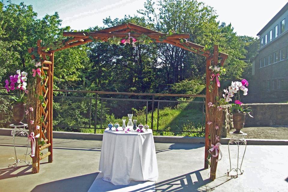 Wedding arch and table set for sand pouring ceremony.  Fresh flowers and rental urns and stands with live orchid plants.