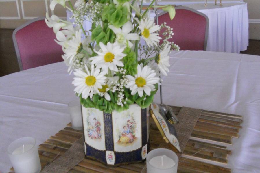 This centerpiece featured an antique metal tin with lid and incorporated daisies, bells of Ireland and dendrobium orchids.