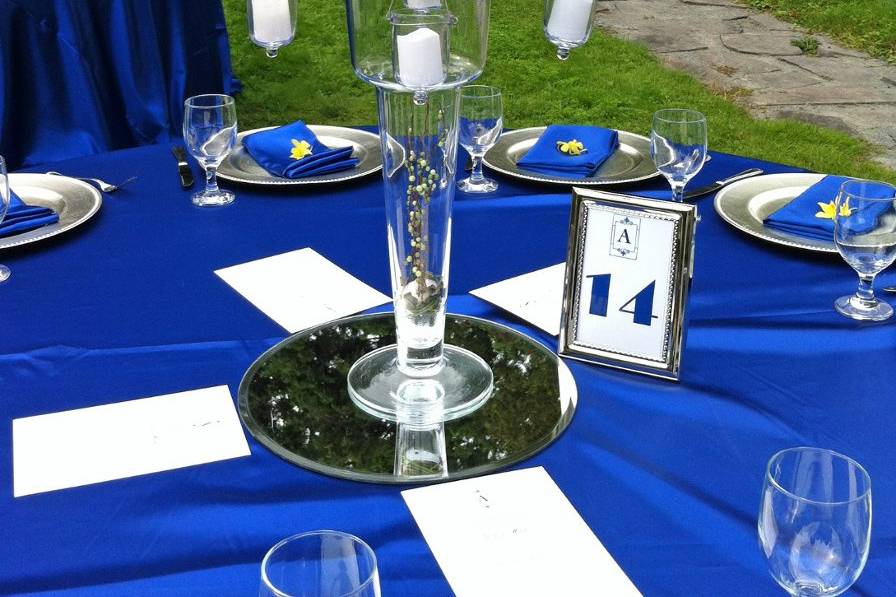 Centerpiece of blues, yellows and greens atop a glass chalice draped with crystals and hanging votives. Dinner was served on the lower lawn at the Mansion at Noble Lane in Bethany, PA.