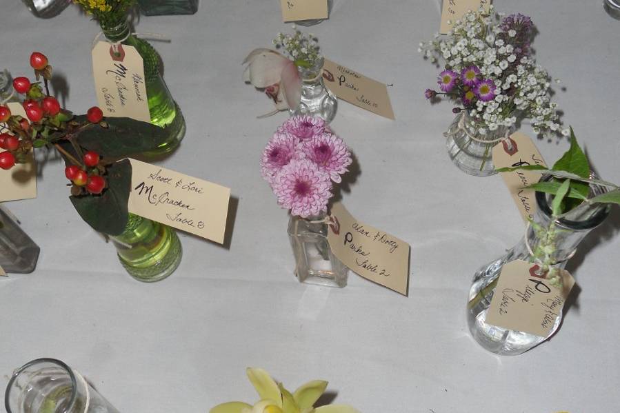 Each table's placecard bottle/vases coordinated with the flowers in the centerpiece of the assigned table.  The placecards served as both, seating assignment and a favor for the guests to bring home.