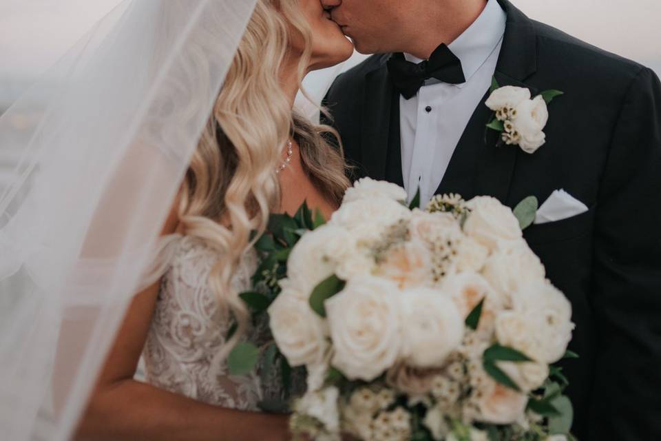 Bride and Groom Kiss Under Vei