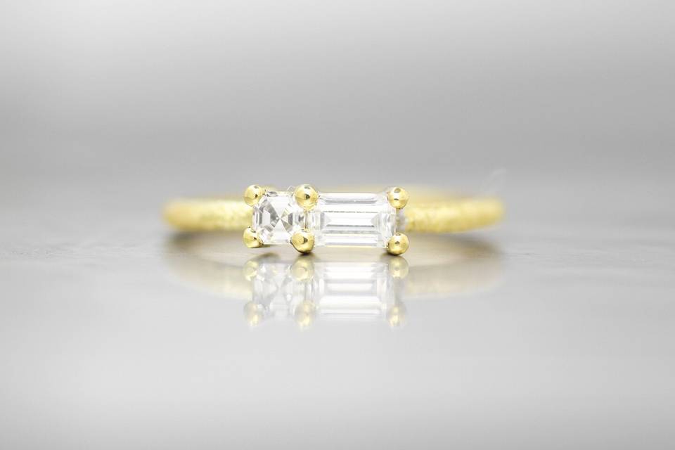 VIENNAThis complimentary pairing creates a beautiful shape along the top of the finger with this unique ring. The sideways emerald cut white diamond is set against an additional asscher white diamond. The signature Wanderlust textured band creates a subtle and organic feel that will wear perfectly over time.