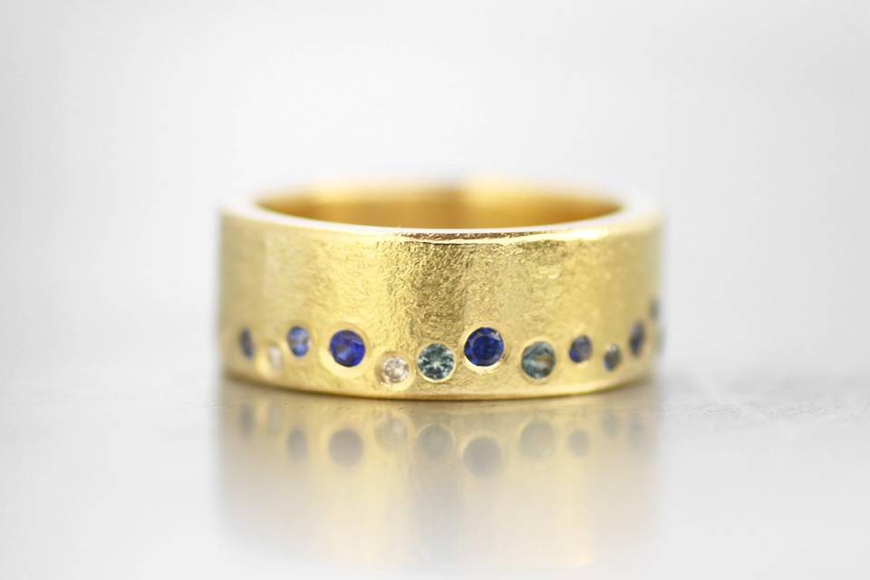 18k yellow gold textured band, with scattered white diamonds and blue sapphires