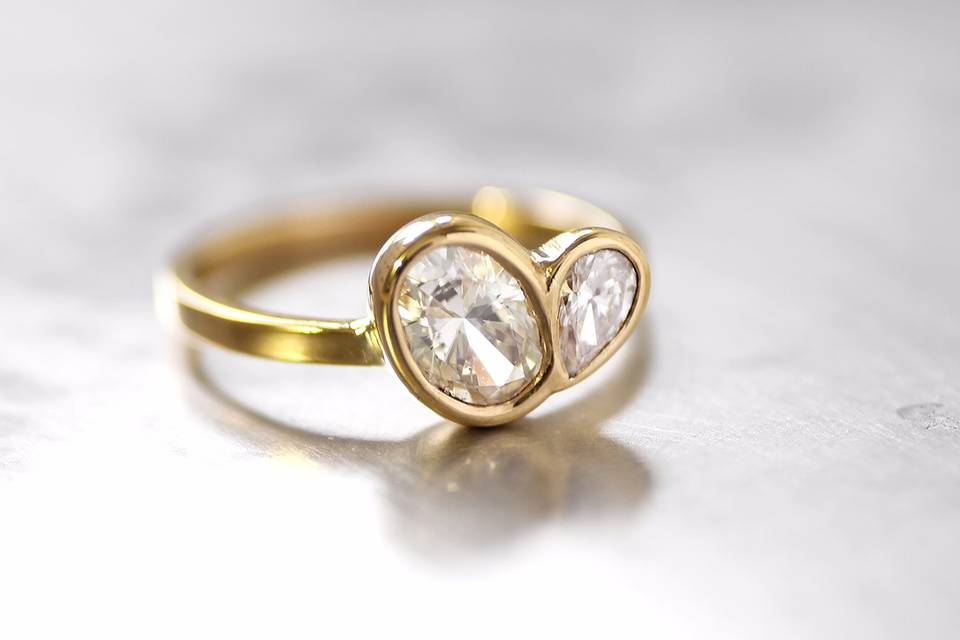 22k yellow gold engagement ring with oval and pear shaped diamond in an offset bezel