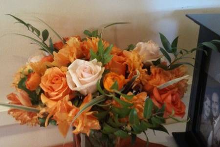 Guest/gift table arrangement #2. Orange, cream, and red-gold roses, orange dahlias, orange ranunculus, and greens.