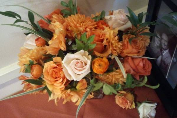 Close-up of arrangement #2. Orange, cream, and red-gold roses, orange dahlias, orange ranunculus, and greens.