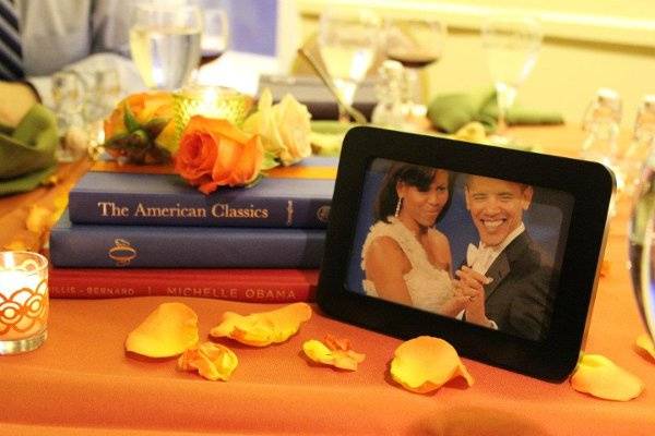 The dinner table centerpieces were made of stacked books, the three different rose varieties around a glass votive, with paper-wrapped votives and orange rose petals scattered around. Each table had a framed photo of a famous couple to 