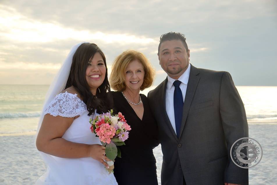 Newlyweds and the officiant at the beach