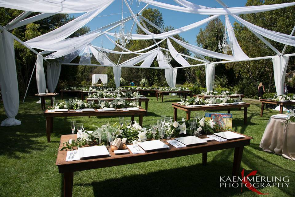 Outdoor wedding reception with farm tables and chandeliers