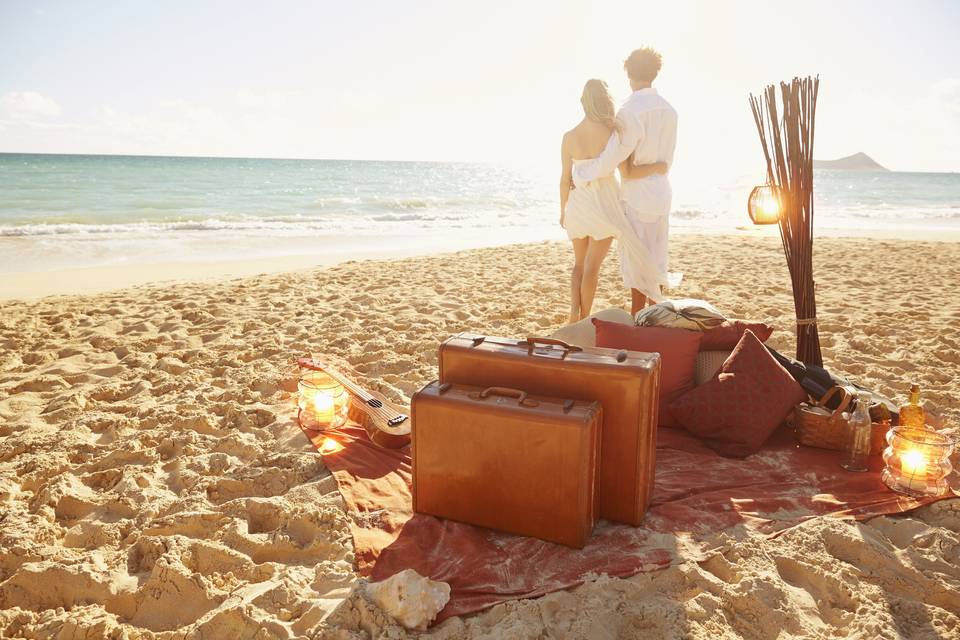 Newlyweds on beach w/luggag