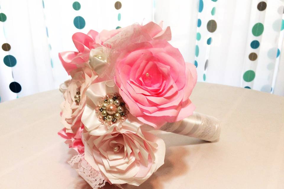Handmade coffee filter paper Roses in shades of pink are used in this bouquet. Mixed in are pearl and rhinestone brooches, lace, ribbon flowers and waves of tulle. The handle is wrapped in white satin ribbon, lace and rhinestone ribbon with organza flowers at the base