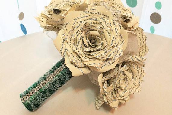 Harry Potter book page bouquets in three different sizes. Bouquet is shown in natural colored Roses surrounded by white tulle. The handle is wrapped in hunter green satin ribbon, white lace and rhinestone ribbon. Colors can be customized.