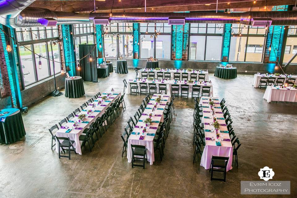 Overhead shot of a industrial warehouse space with spectacular uplights and colorful napkins.